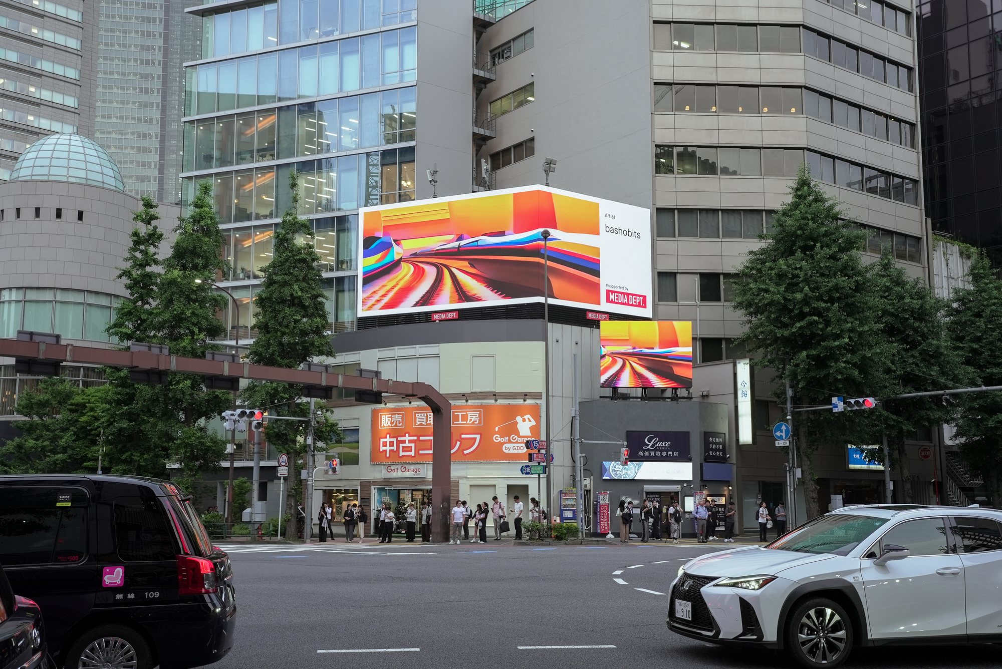 The work wrapping both faces of a double-sided screen above a Tokyo intersection, in orange and yellow