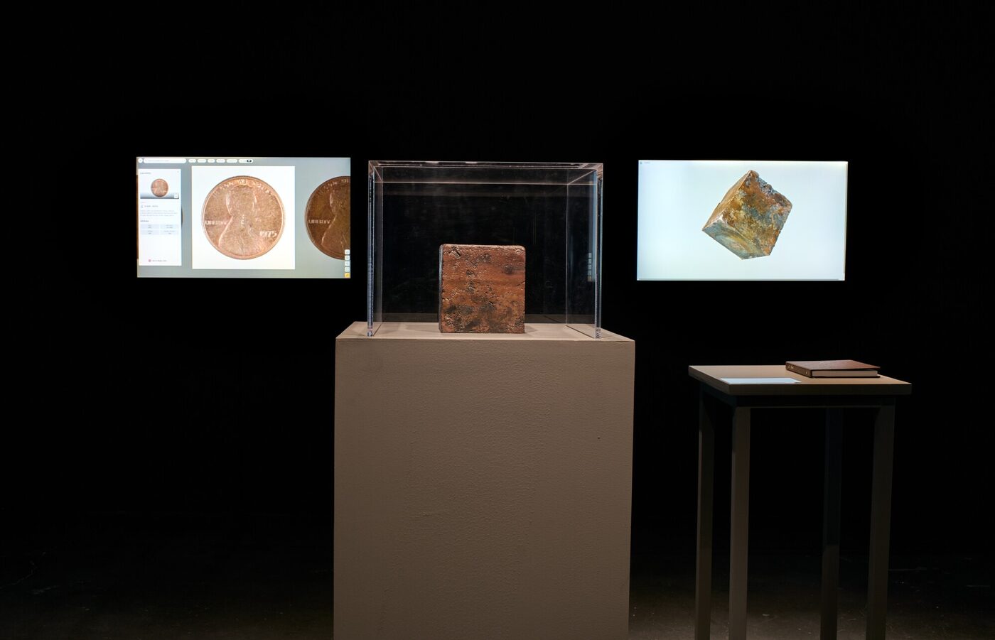 The copper block in a vitrine at UCCA Beijing, flanked by screens showing the catalogued cents and the three-dimensional model